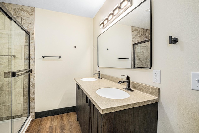 bathroom with hardwood / wood-style flooring, vanity, and a shower with door