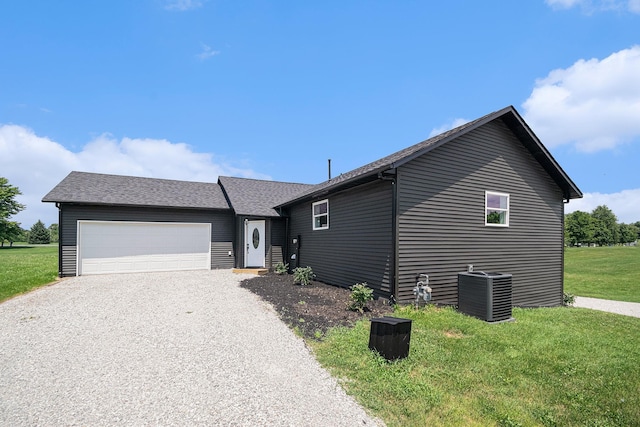 view of front of property with central AC unit, a garage, and a front yard