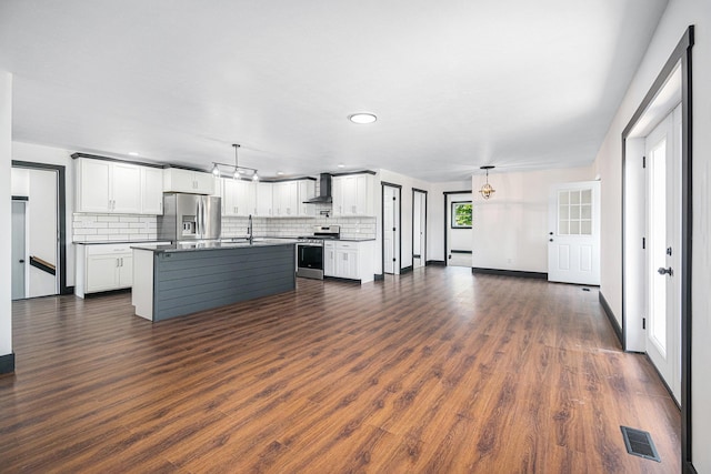 kitchen featuring dark hardwood / wood-style floors, pendant lighting, stainless steel appliances, a kitchen island with sink, and white cabinets