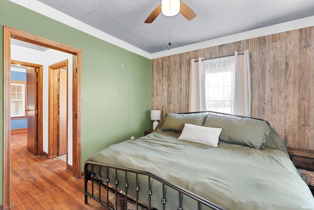 bedroom with wood-type flooring, ceiling fan, and wood walls