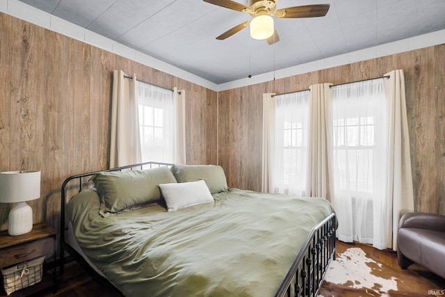 bedroom featuring ceiling fan and wooden walls