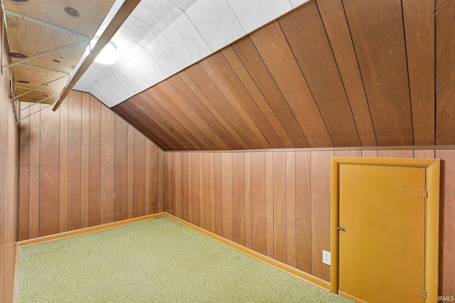 additional living space with vaulted ceiling, carpet, and wooden walls