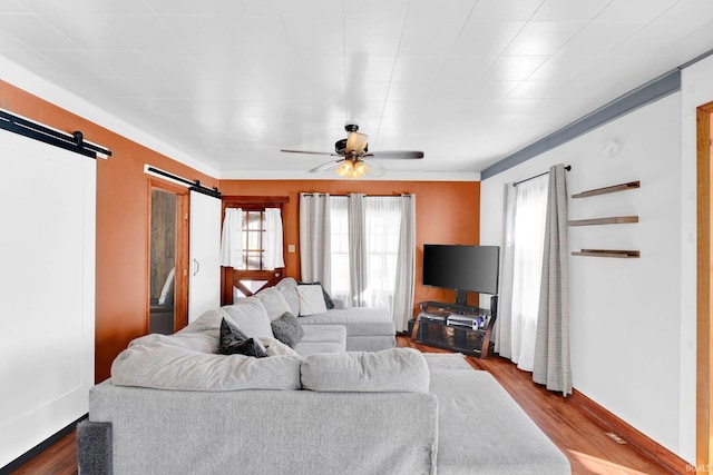 living room with a barn door, hardwood / wood-style floors, and ceiling fan