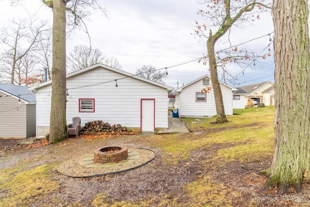 back of house featuring a storage shed, an outdoor fire pit, and a lawn