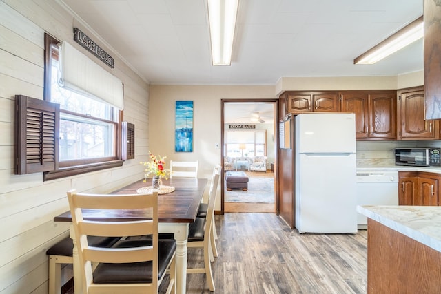 kitchen featuring crown molding, white appliances, wooden walls, and light hardwood / wood-style flooring