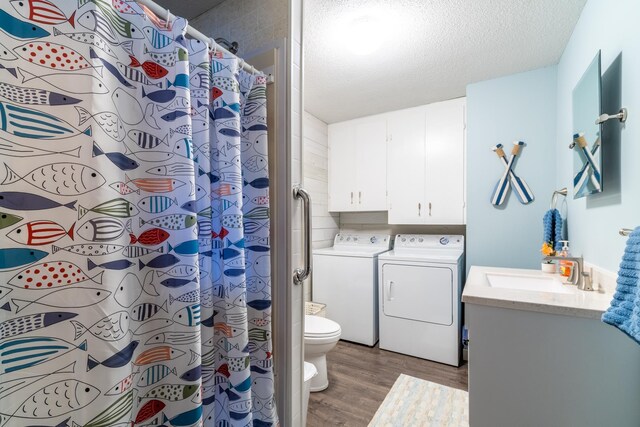 bathroom featuring washer and dryer, hardwood / wood-style floors, vanity, toilet, and a textured ceiling