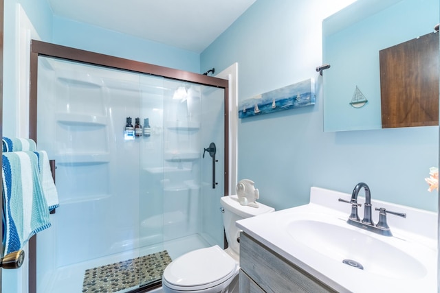 bathroom with toilet, vanity, and a shower with shower door