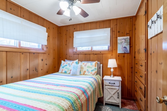 bedroom with ceiling fan and wood walls