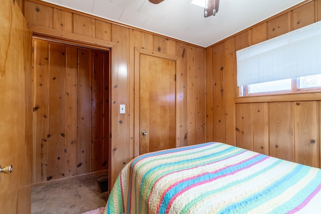 bedroom featuring ceiling fan, carpet flooring, and wooden walls