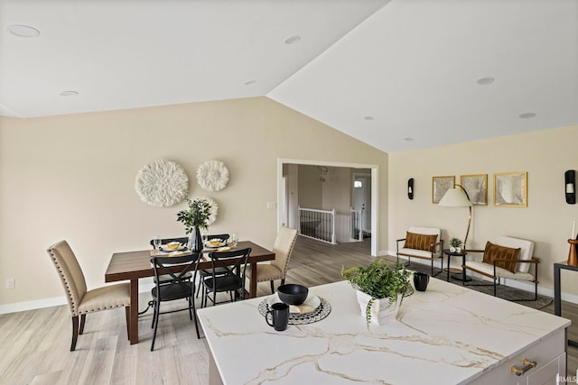 dining room with lofted ceiling and light wood-type flooring