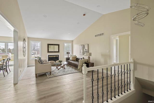 living room featuring a healthy amount of sunlight, high vaulted ceiling, and light wood-type flooring