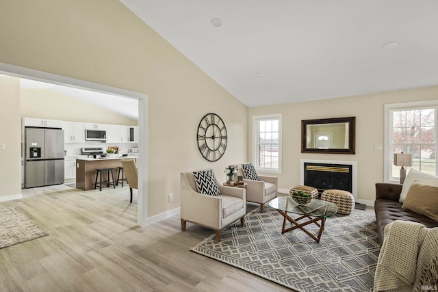 living room with vaulted ceiling, light hardwood / wood-style floors, and a healthy amount of sunlight