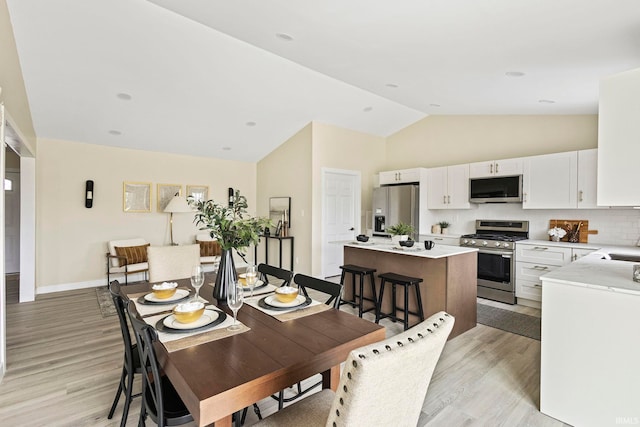 dining room featuring lofted ceiling and light wood-type flooring