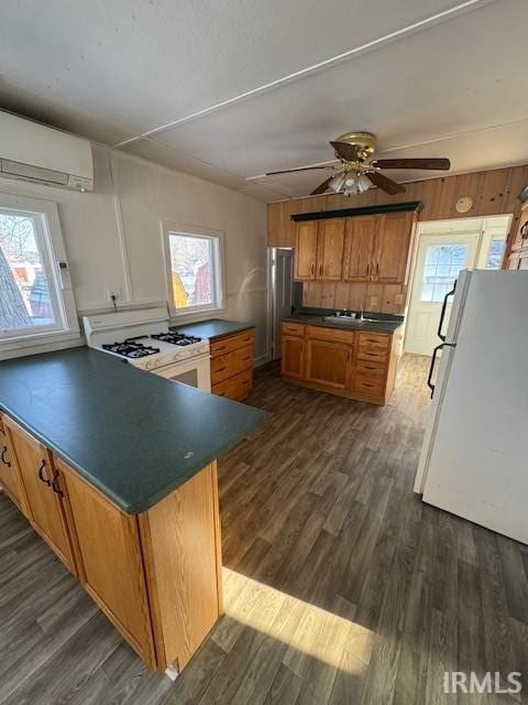 kitchen featuring a healthy amount of sunlight, white appliances, dark hardwood / wood-style floors, and a wall mounted AC