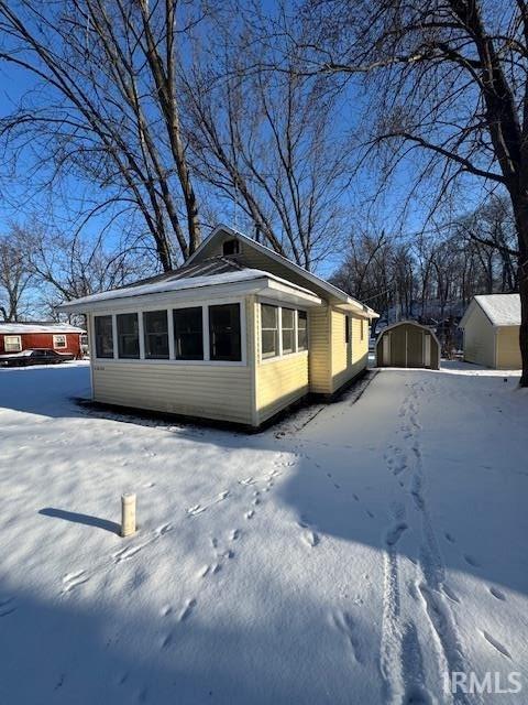 view of snowy exterior with a shed