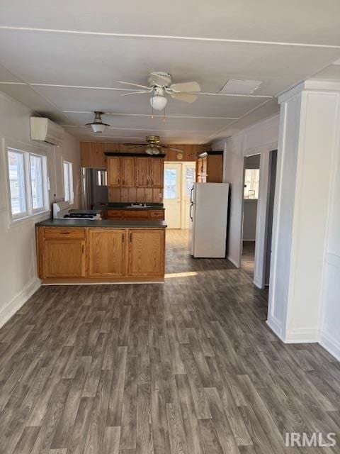 kitchen featuring dark wood-type flooring, an AC wall unit, kitchen peninsula, white fridge, and ceiling fan