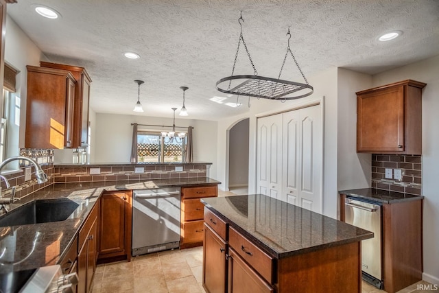 kitchen with sink, stainless steel dishwasher, a center island, and dark stone counters