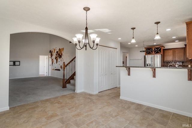 kitchen featuring stainless steel fridge with ice dispenser, light carpet, a kitchen breakfast bar, pendant lighting, and decorative backsplash