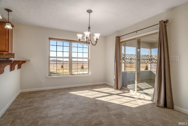 unfurnished dining area featuring an inviting chandelier, plenty of natural light, and a textured ceiling