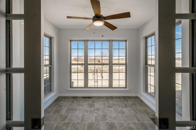 unfurnished sunroom featuring plenty of natural light and ceiling fan