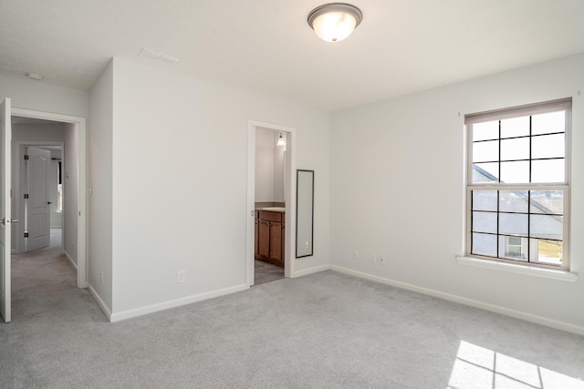 unfurnished bedroom featuring light carpet and ensuite bath