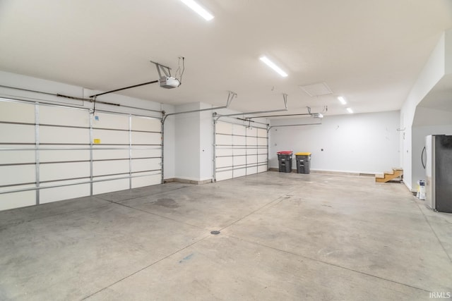 garage with a garage door opener and stainless steel fridge