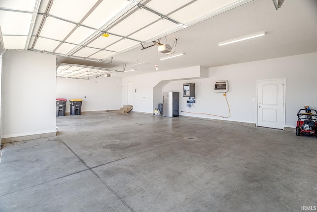 garage featuring heating unit, a garage door opener, stainless steel fridge, and electric panel