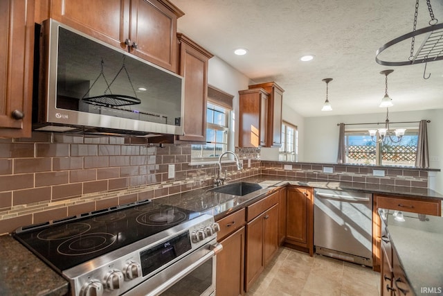 kitchen featuring sink, a textured ceiling, pendant lighting, stainless steel appliances, and backsplash