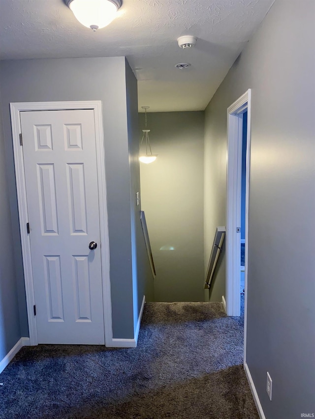 stairs with carpet floors and a textured ceiling