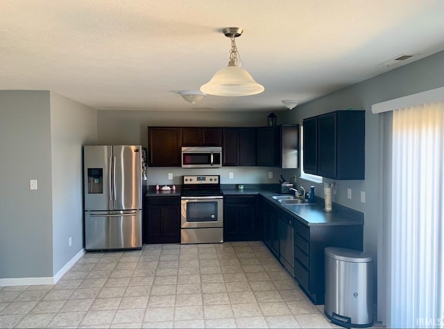 kitchen with dark brown cabinetry, stainless steel appliances, sink, and hanging light fixtures