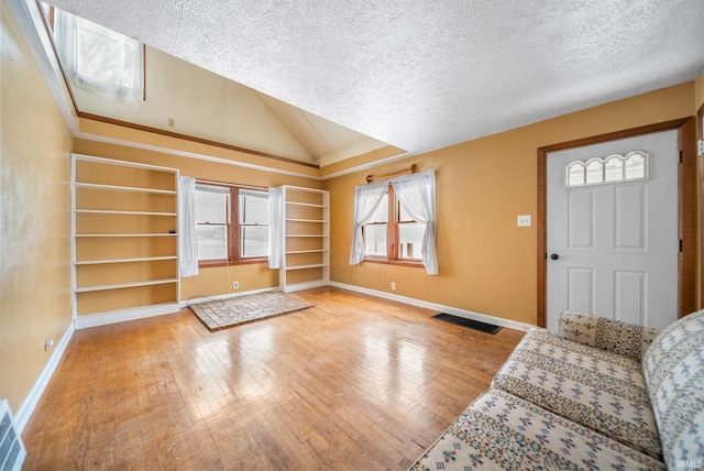 entryway with wood-type flooring, vaulted ceiling, and a textured ceiling