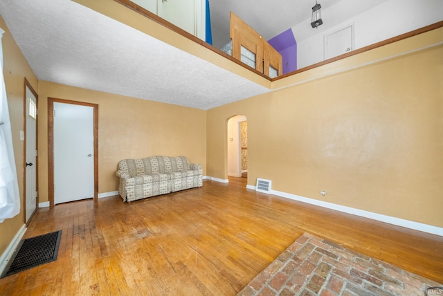 unfurnished room with a towering ceiling, wood-type flooring, and a textured ceiling