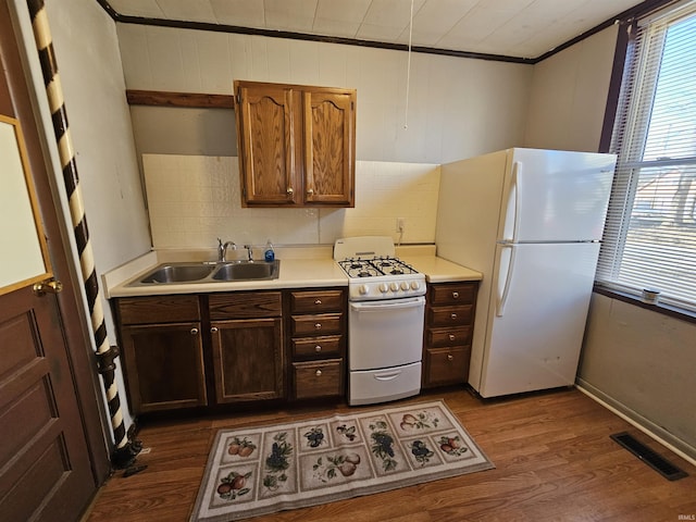 kitchen featuring sink, crown molding, dark hardwood / wood-style floors, white appliances, and decorative backsplash