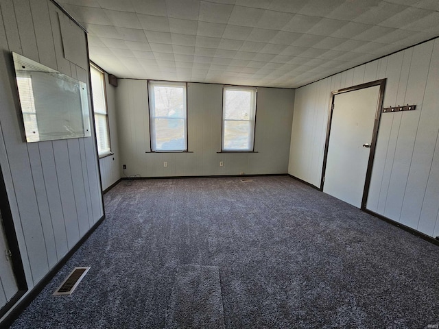 unfurnished bedroom with dark carpet and wood walls