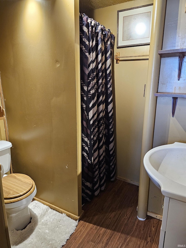 bathroom with hardwood / wood-style flooring, a shower with shower curtain, and toilet