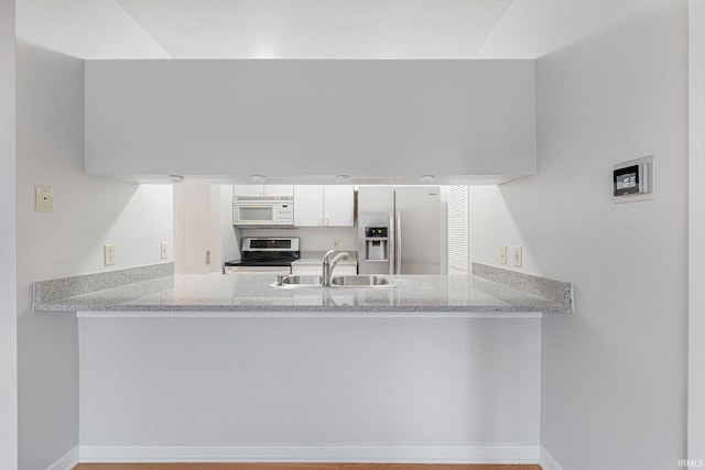 kitchen featuring light stone counters, sink, stainless steel appliances, and white cabinets