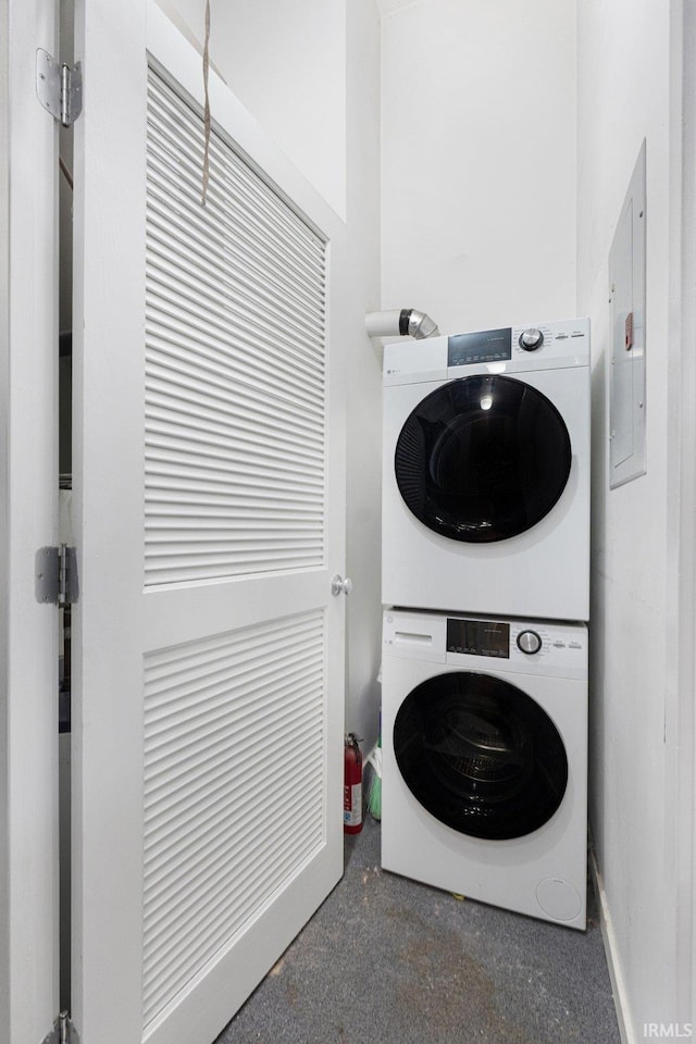 washroom featuring stacked washer / drying machine and electric panel