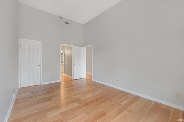 unfurnished bedroom featuring a high ceiling and light hardwood / wood-style floors