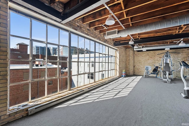 interior space featuring a healthy amount of sunlight, brick wall, and carpet