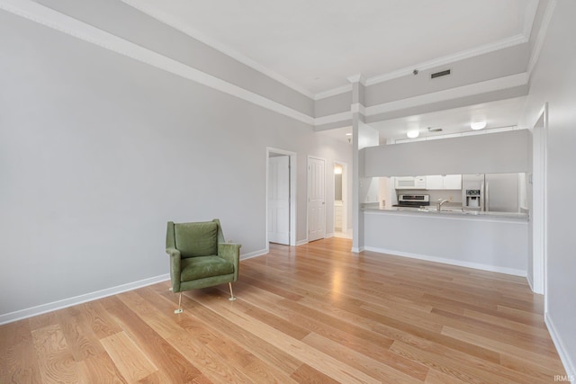 unfurnished room featuring sink, ornamental molding, and light hardwood / wood-style floors