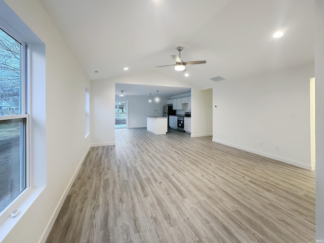 unfurnished living room with lofted ceiling, sink, light hardwood / wood-style flooring, and ceiling fan