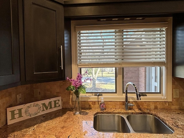 kitchen featuring sink, dark brown cabinets, and light stone countertops