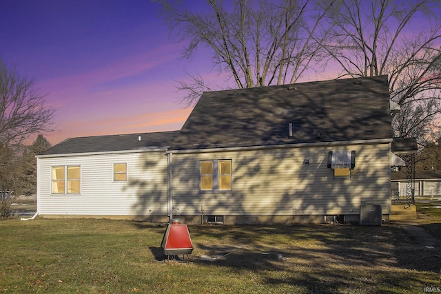 back house at dusk with a lawn