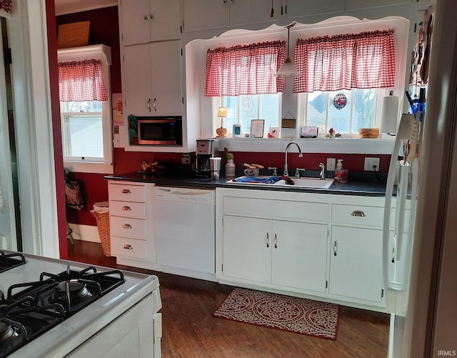 kitchen with sink, white appliances, white cabinetry, plenty of natural light, and dark hardwood / wood-style floors