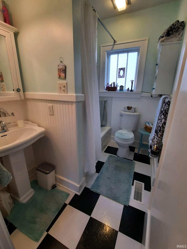 full bathroom featuring sink, shower / bath combo with shower curtain, and toilet