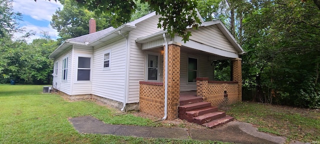 bungalow featuring a porch, a front lawn, and central air condition unit