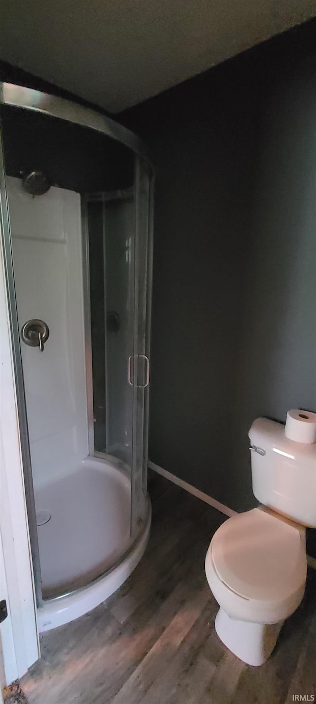 bathroom with hardwood / wood-style floors, an enclosed shower, and toilet