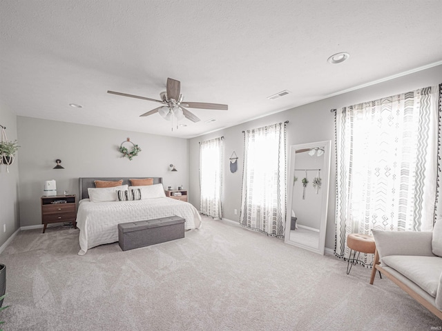 bedroom featuring light colored carpet, a textured ceiling, and ceiling fan