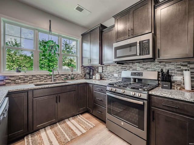 kitchen featuring light stone counters, sink, and appliances with stainless steel finishes