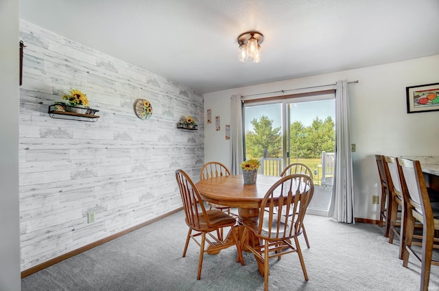 dining space featuring light carpet and wood walls